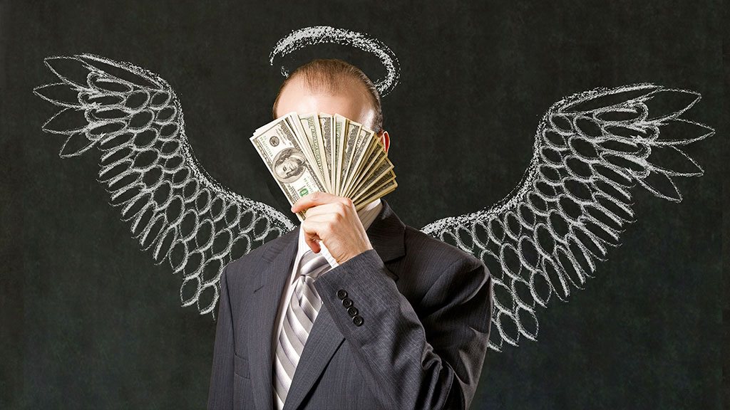 мужчина в костюме с крыльями держит пачку доларов